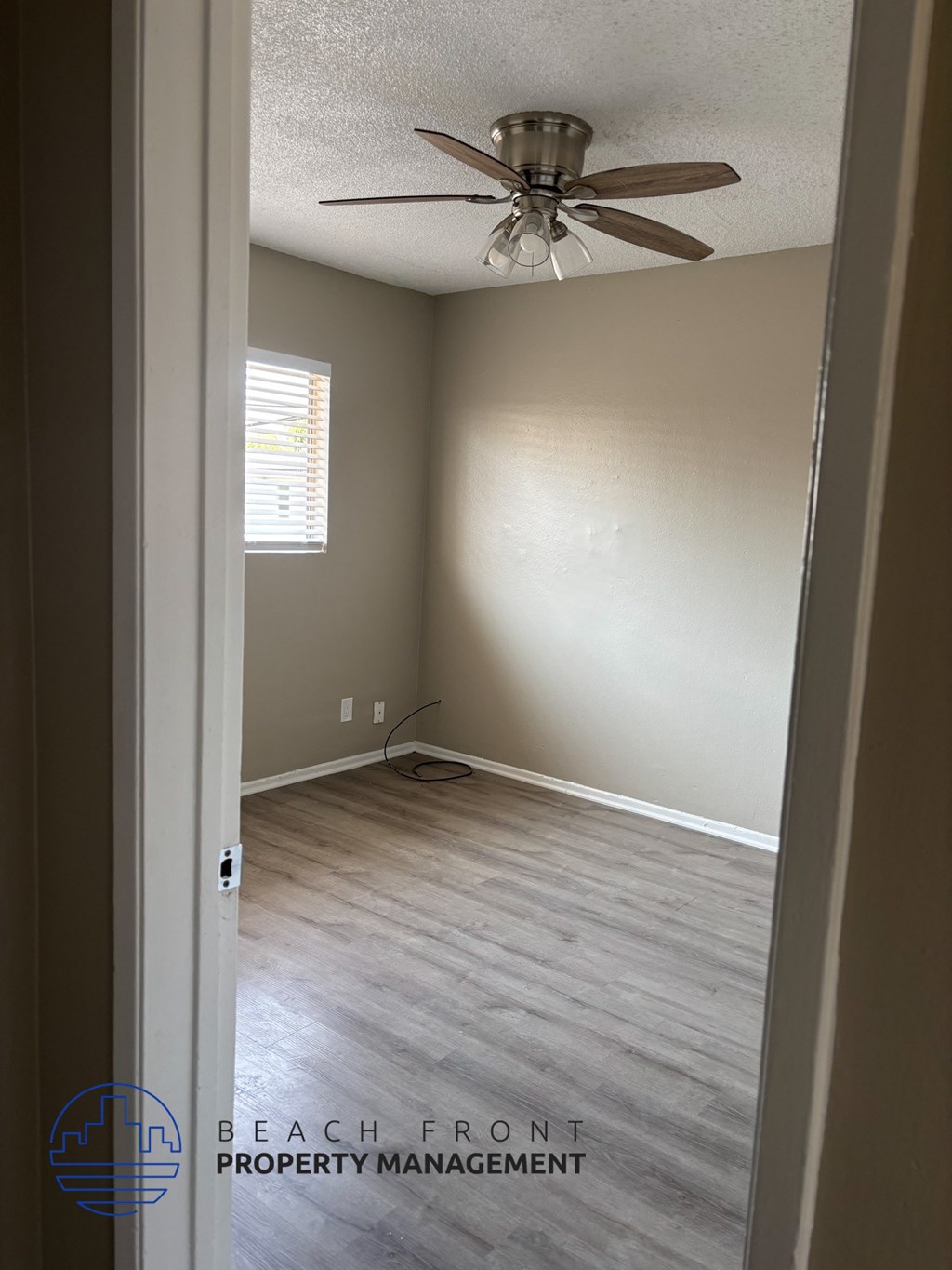 A room with a ceiling fan and wooden flooring.